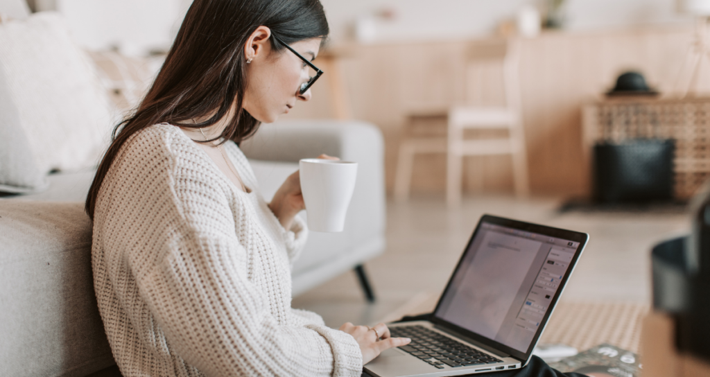 woman hold a cup while using laptop