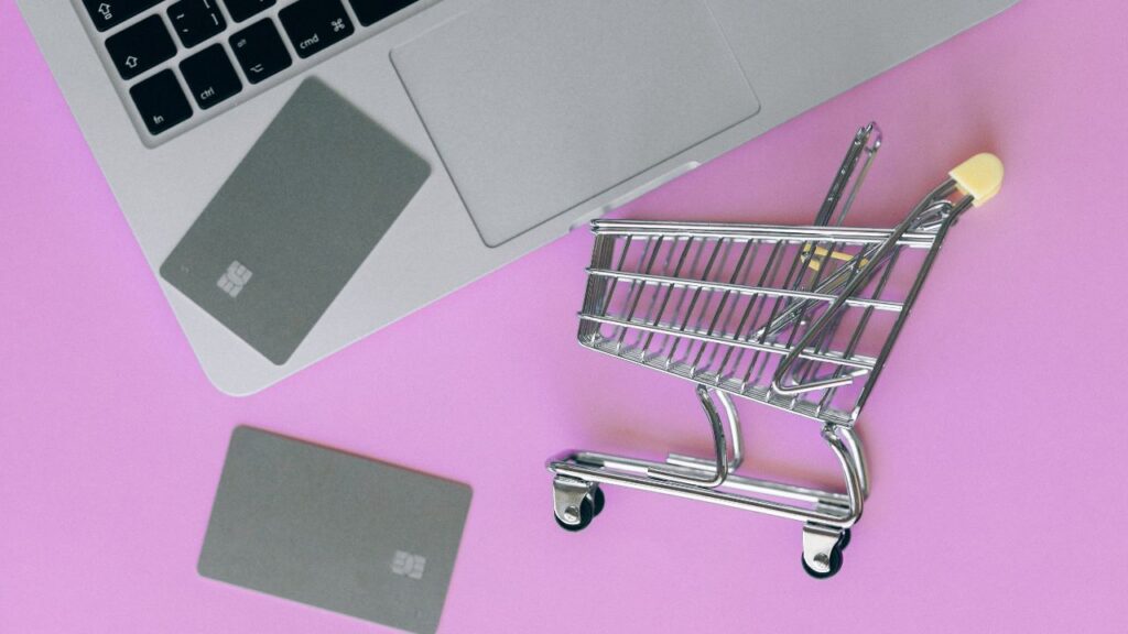 shopping cart and cards next to laptop