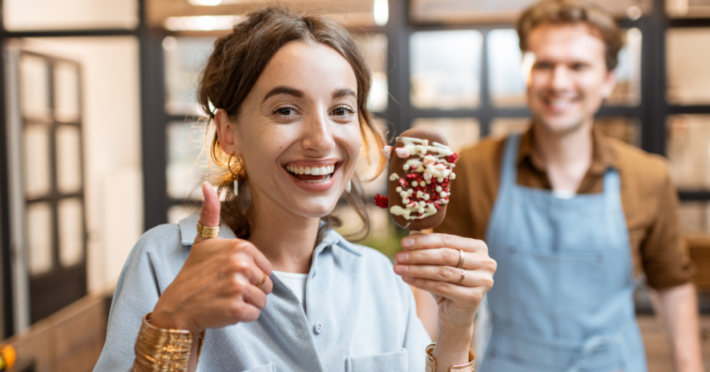 a woman holds an ice cream and thumbs up